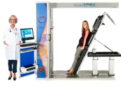 The Accu-SPINA IDD Therapy table standing upright, with a client stepping on and a clinician at the console