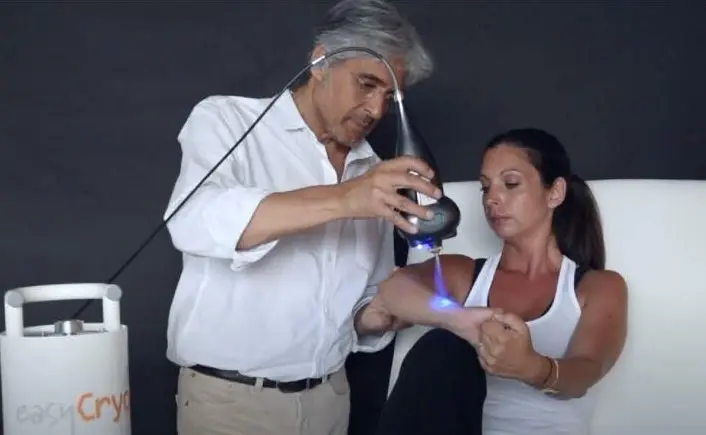 A practitioner treating a woman’s elbow with a SubZero cryotherapy handpiece